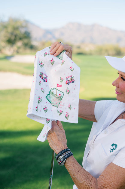 Snuggle Bug Golf Arizona Bloom waffle microfiber towel with floral and golf cart print held on a green golf course