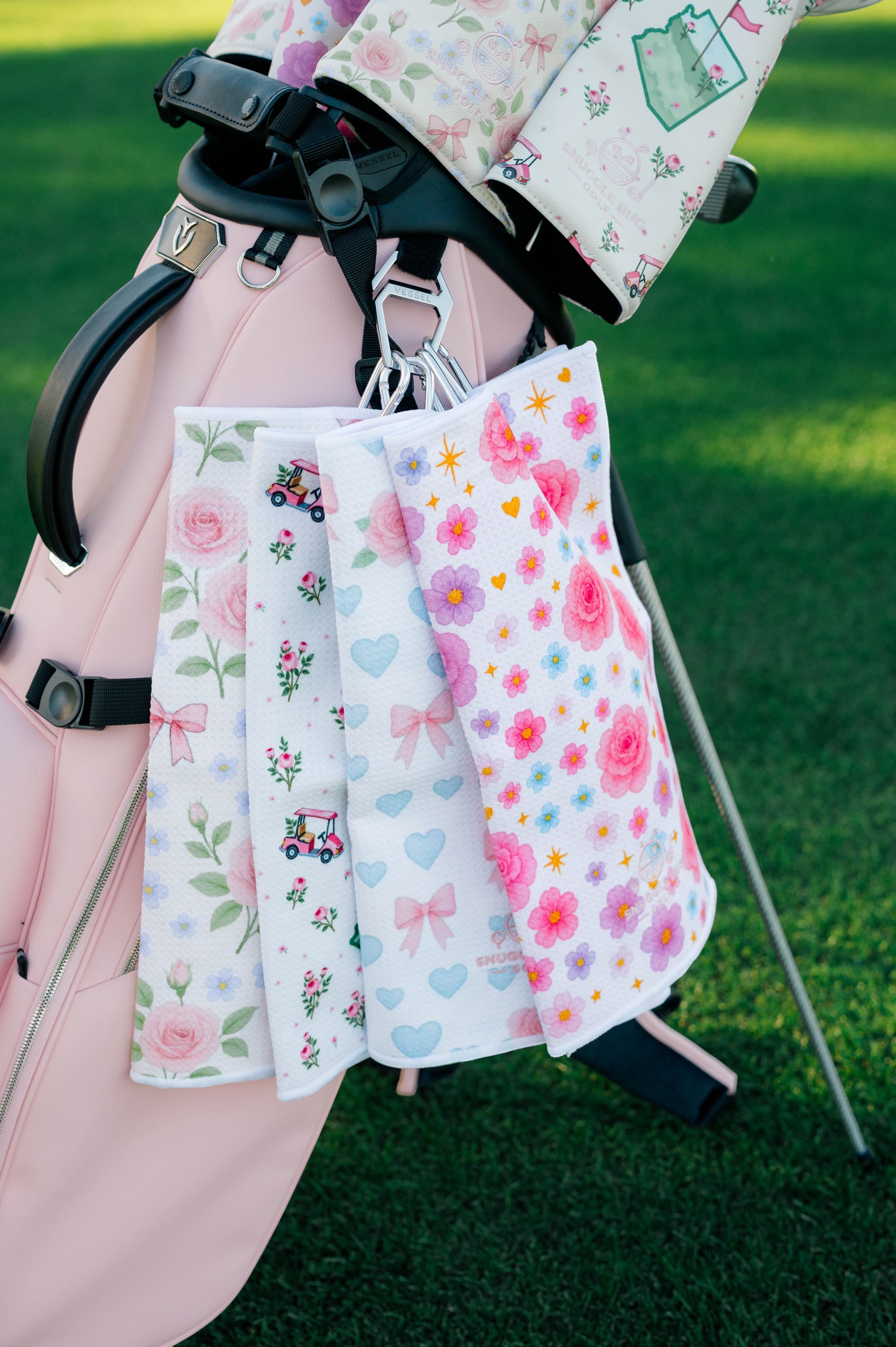 Snuggle Bug Golf Arizona Bloom microfiber waffle golf towels with floral and golf cart patterns hanging on a golf bag.