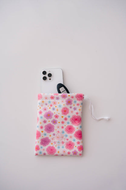 Snuggle Bug Golf Starlight Bloom drawstring pouch featuring pink florals, violet daisies, and stars with a phone.