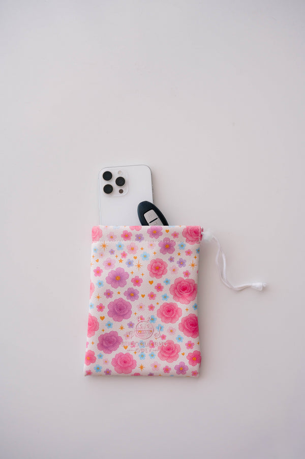 Snuggle Bug Golf Starlight Bloom drawstring pouch featuring pink florals, violet daisies, and stars with a phone.