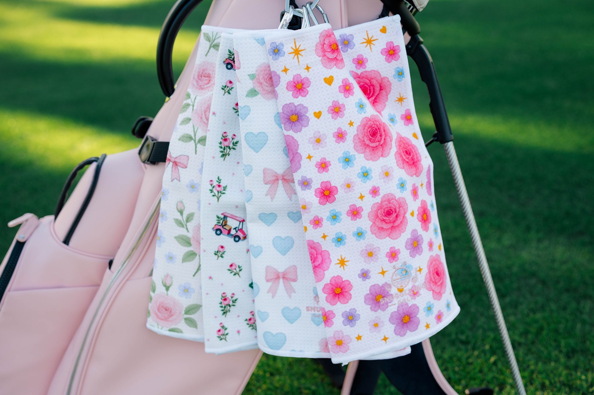Snuggle Bug Golf Starlight Bloom waffle microfiber towel with pink roses, stars, and hearts hanging on a golf bag.