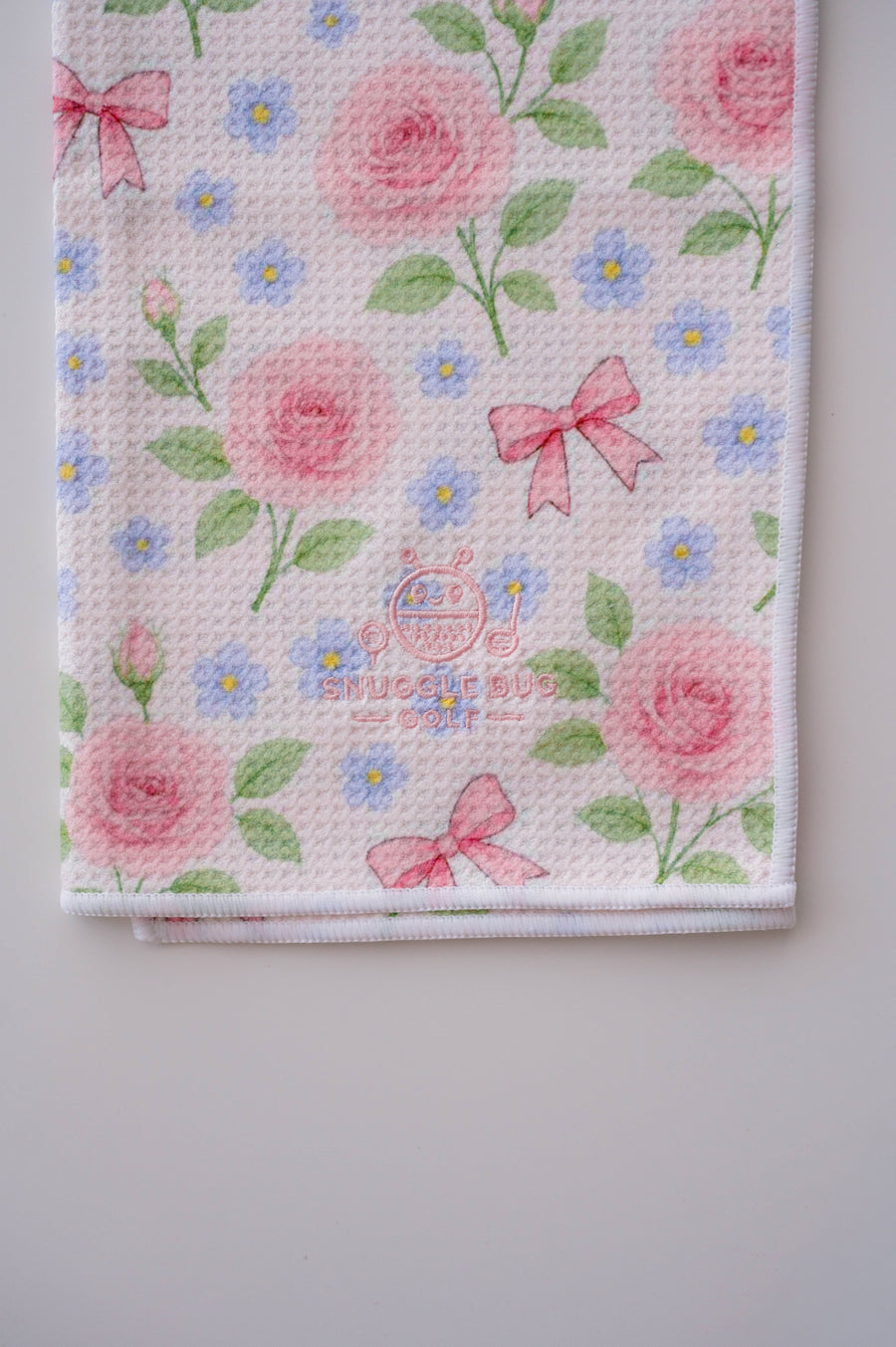 Snuggle Bug Golf Whisper Rose microfiber golf towel with pink roses, blue flowers, and bows on a waffle texture.